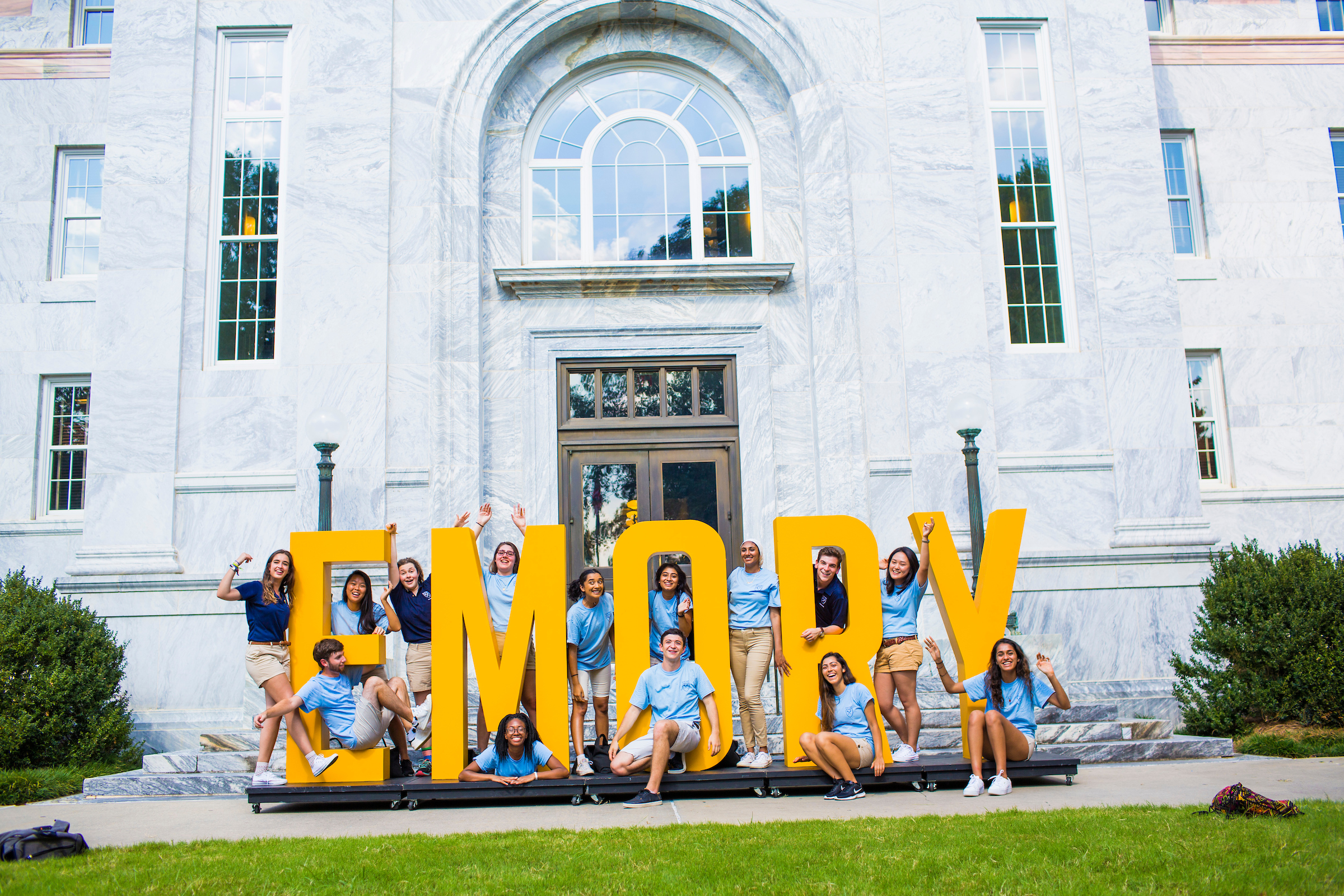 emory students sitting on an Emory sign